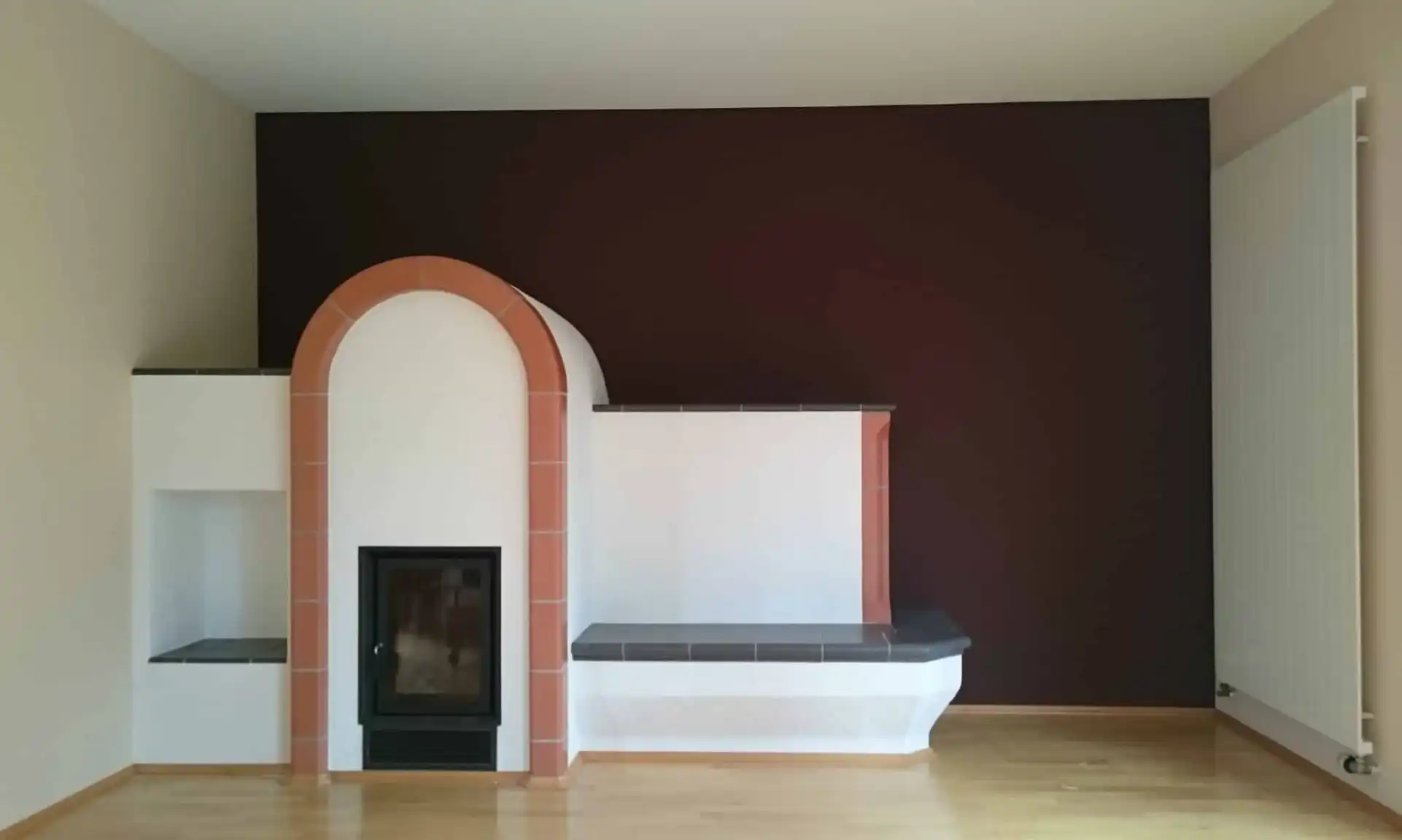Matte Akzentwand in einem tiefen Braunton, gestaltet mit ökologischer Kreidefarbe hinter einem modern eingefassten Kamin.
